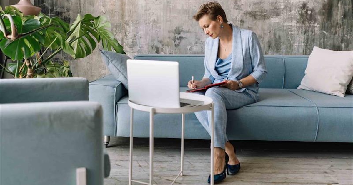 Person sitting on a couch while looking at a computer Person sitting on a couch while looking at a computer