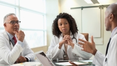 Three people sit around a table