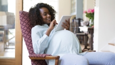 Pregnant person sitting in a chair looking at a tablet