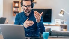 Worker with headphones conducting meeting on laptop