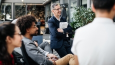 Numerous people sitting in a courtyard and looking at something off camera Numerous people sitting in a courtyard and looking at something off camera