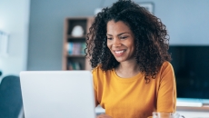 Person sitting at a computer looking at the screen while smiling Person sitting at a computer looking at the screen while smiling