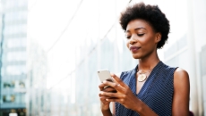 Person standing in front of a building while looking at their phone Person standing in front of a building while looking at their phone