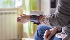 Person sitting on a bed with a wearable on their wrist