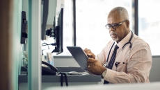 Healthcare provider sitting at a desk while looking at a tablet