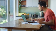 Person sitting at a table while looking at a computer Person sitting at a table while looking at a computer