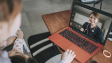 Person sitting down looking at a computer on a coffee table, talking to a healthcare provider