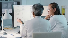 Healthcare workers looking at a spreadsheet on a computer monitor