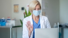A doctor recording a video on her laptop.