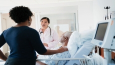 A doctor talks to a man and his loved one at a hospital