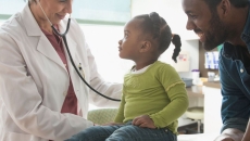 Healthcare provider examining a patient while their caregiver stands nearby watching