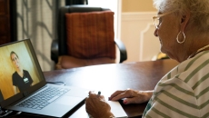Person sitting in front of a computer while talking to a virtual healthcare provider