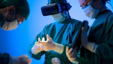 Three healthcare providers in the surgery setting with one wearing a virtual reality headset