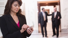 Person standing in a corridor with two other people behind them walking