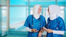 Nurses wearing hijabs conversing while holding their smartphones